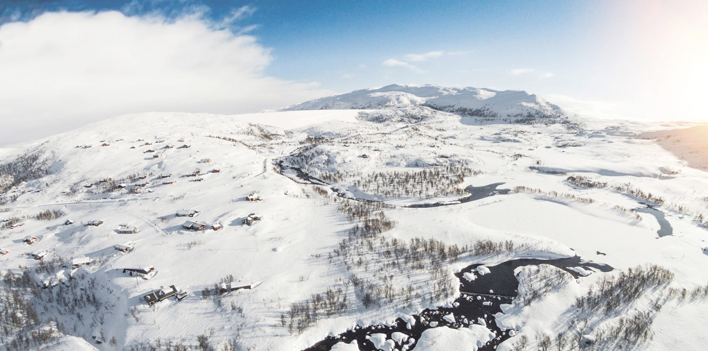 Flyfoto over hyttefeltet i Sysendalen med snødekte fjell i bakgrunnen